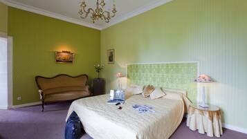 A bedroom with a bed, a chair, a lamp, and a dresser.