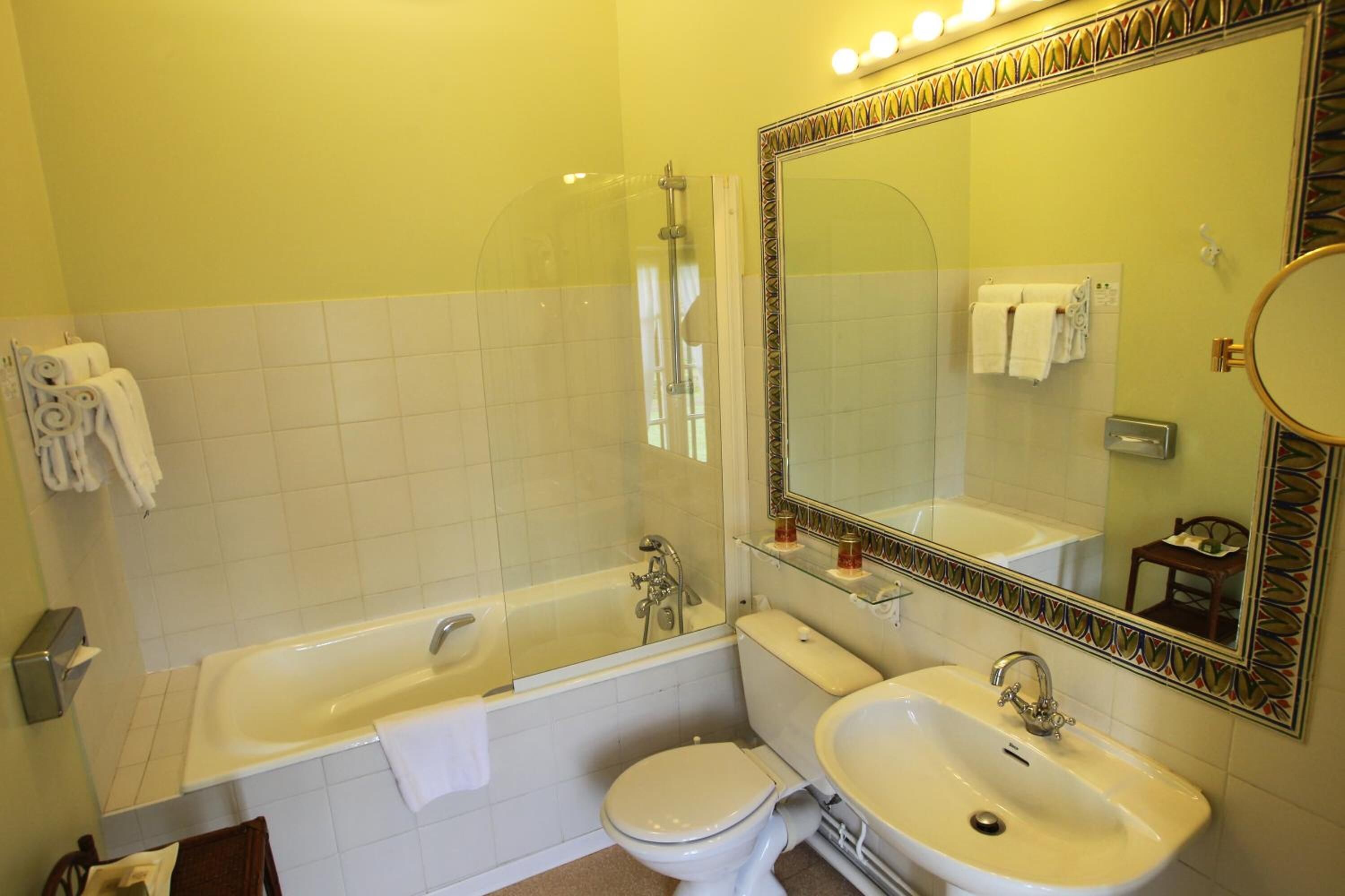 Een badkamer met bad, toilet en wastafel, plus een grote spiegel en een douchecabine.