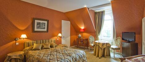 Habitación de hotel con una cama grande, un escritorio con silla, televisor y ventana con cortinas.