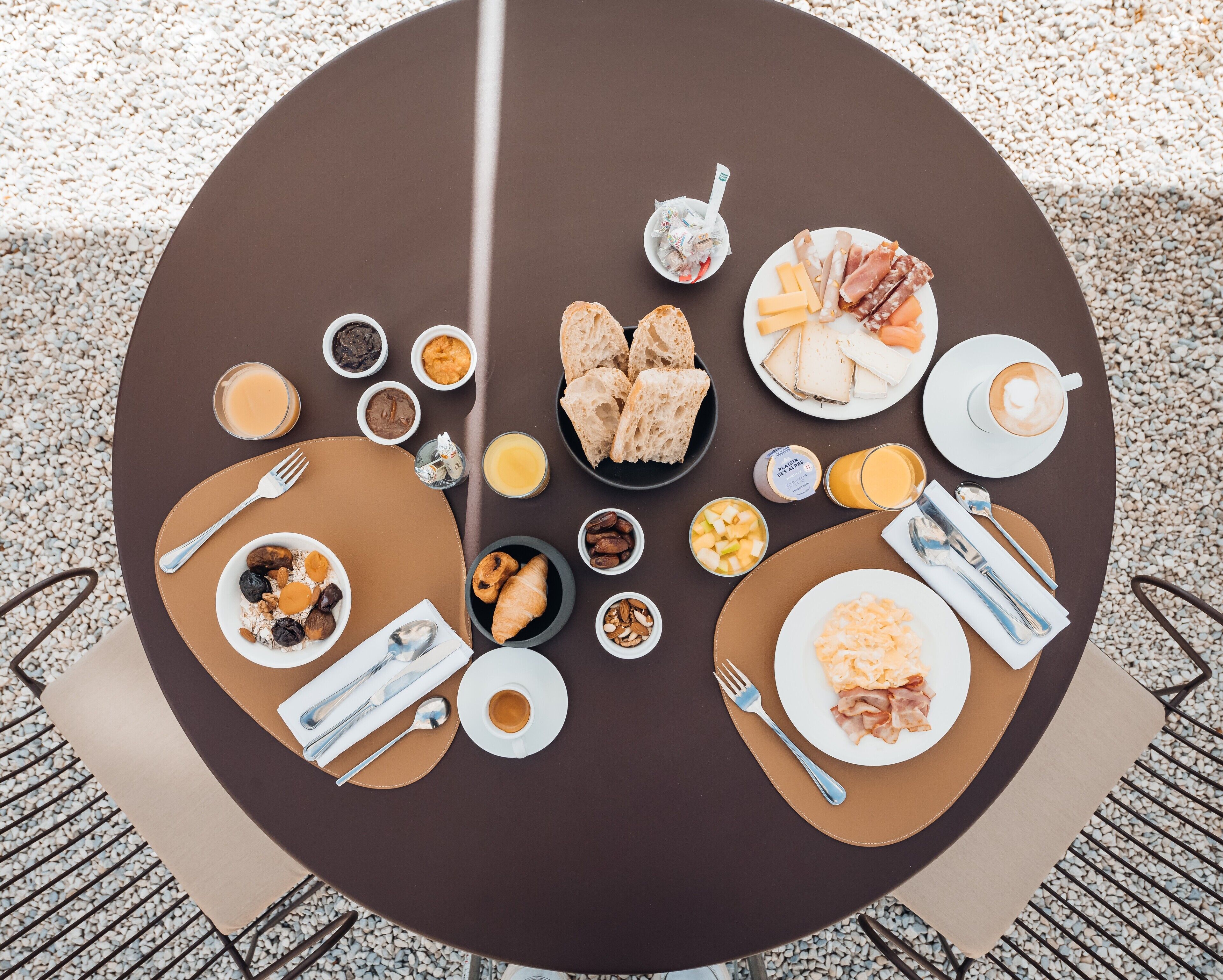 A round table with various breakfast items including croissants, cheese, and coffee.