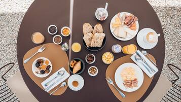A round table with various breakfast items including croissants, cheese, and coffee.
