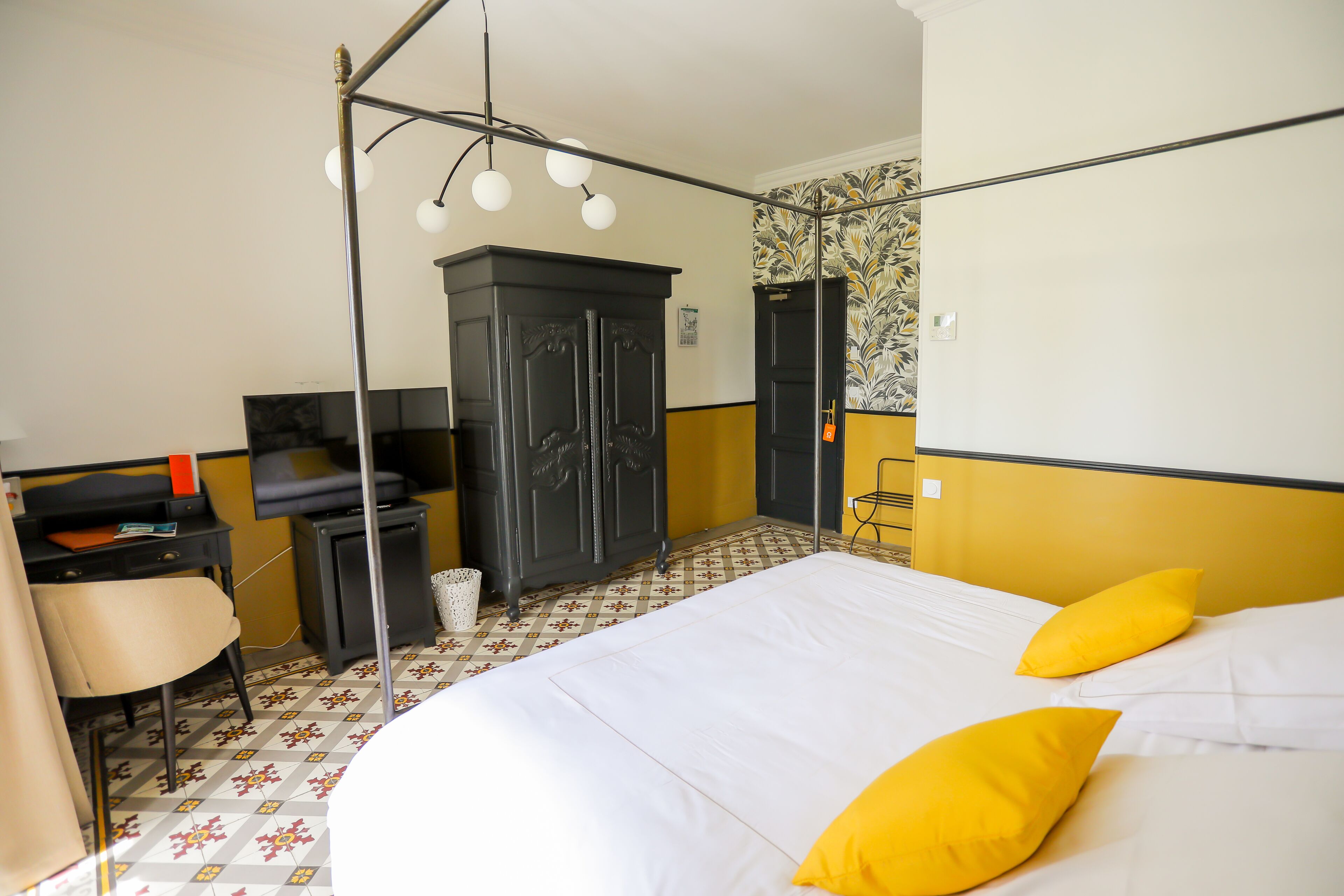 A hotel room with a bed, a desk, a chair, a wardrobe, and a mirror.