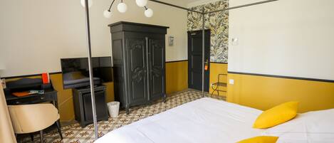 A hotel room with a bed, a desk, a chair, a wardrobe, and a mirror.