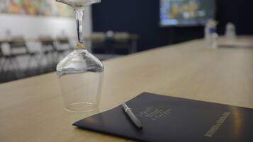 A conference table with a glass vase, a pen, and a black folder with text.