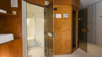 Interior de madera con puerta de ducha de vidrio, toallero y señal que indica zona de sauna.