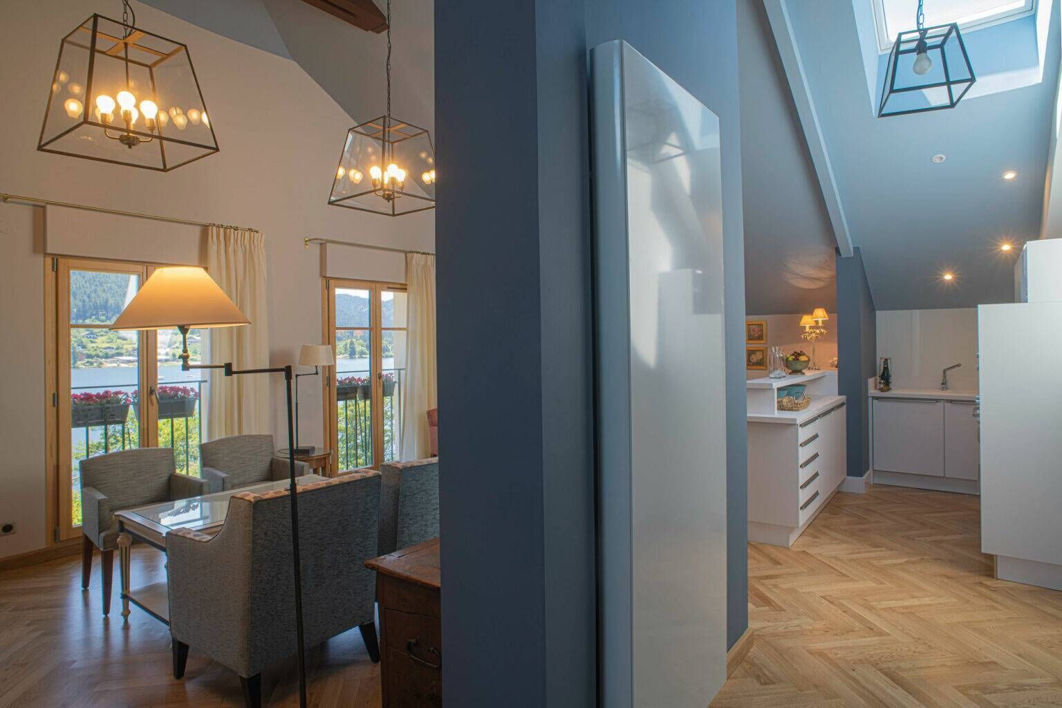 Una cocina moderna con armarios blancos, encimera de madera y vistas a un balcón con plantas.