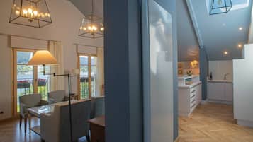 A modern kitchen with white cabinets, a wooden countertop, and a view of a balcony with plants.