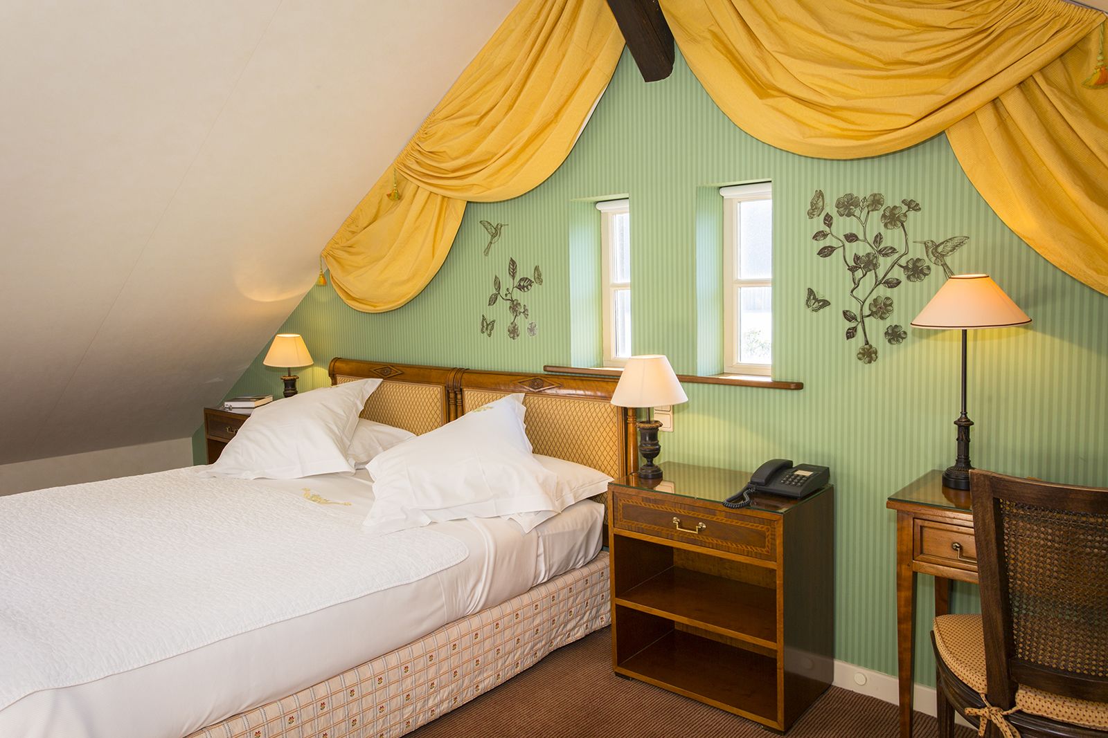 Een slaapkamer met een bed, twee nachtkastjes, een stoel en een lamp.