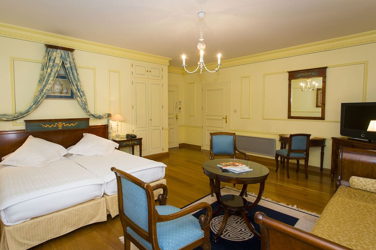 Une chambre d’hôtel avec deux lits, une table à manger, un téléviseur et un miroir.