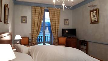 Une chambre d’hôtel avec un grand lit, une télévision, un lustre et des rideaux.