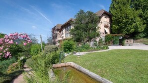 Een traditioneel huis met een tuin, een kleine vijver en een pad naar de ingang.