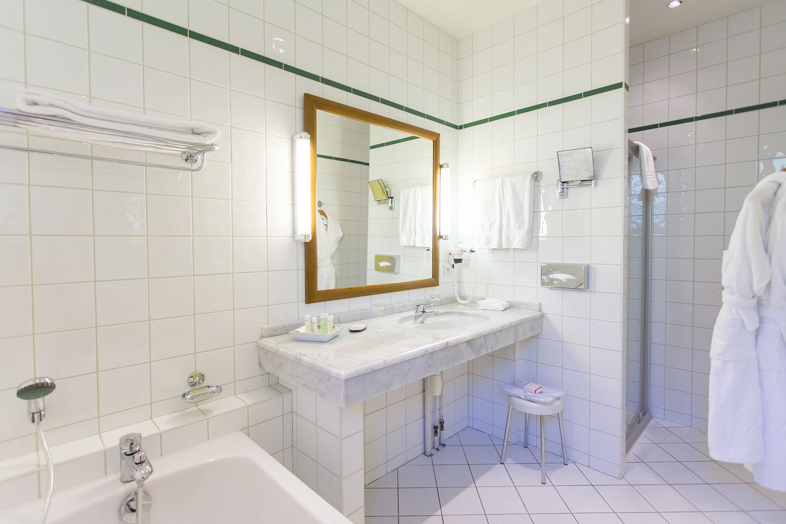 Un baño moderno con dos lavamanos, una bañera, un espejo grande y cabina de ducha a ras de suelo.