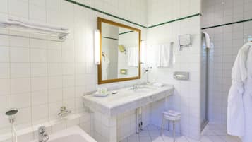 Un baño moderno con dos lavamanos, una bañera, un espejo grande y cabina de ducha a ras de suelo.