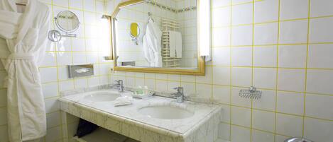 Un baño con dos lavamanos, una bañera y un espejo.