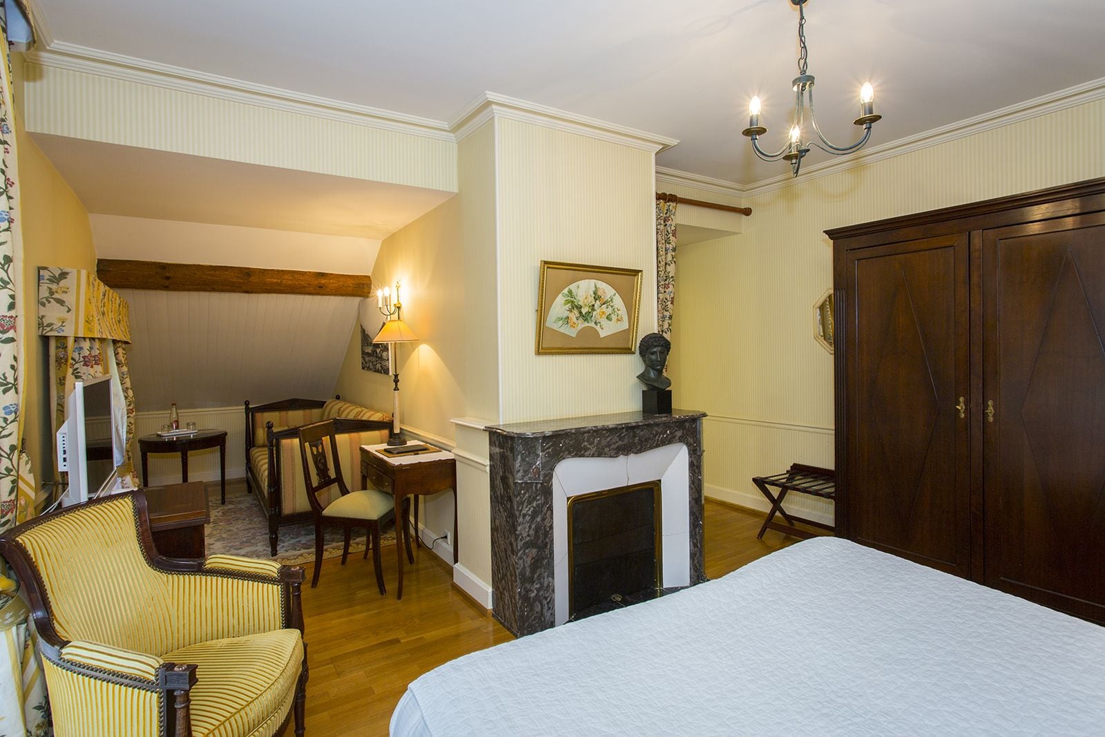 Une chambre d’hôtel comprenant un lit, un bureau, une chaise, une cheminée et une armoire.