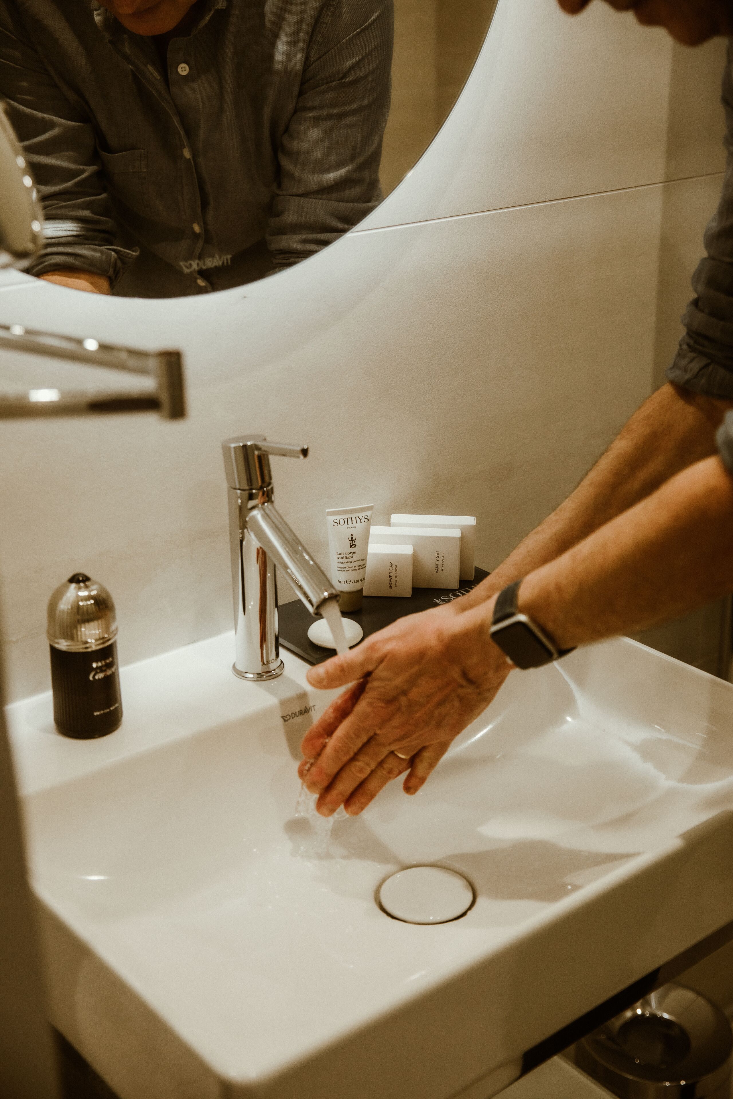 A person washing hands at a sink with a modern faucet and soap dispenser.