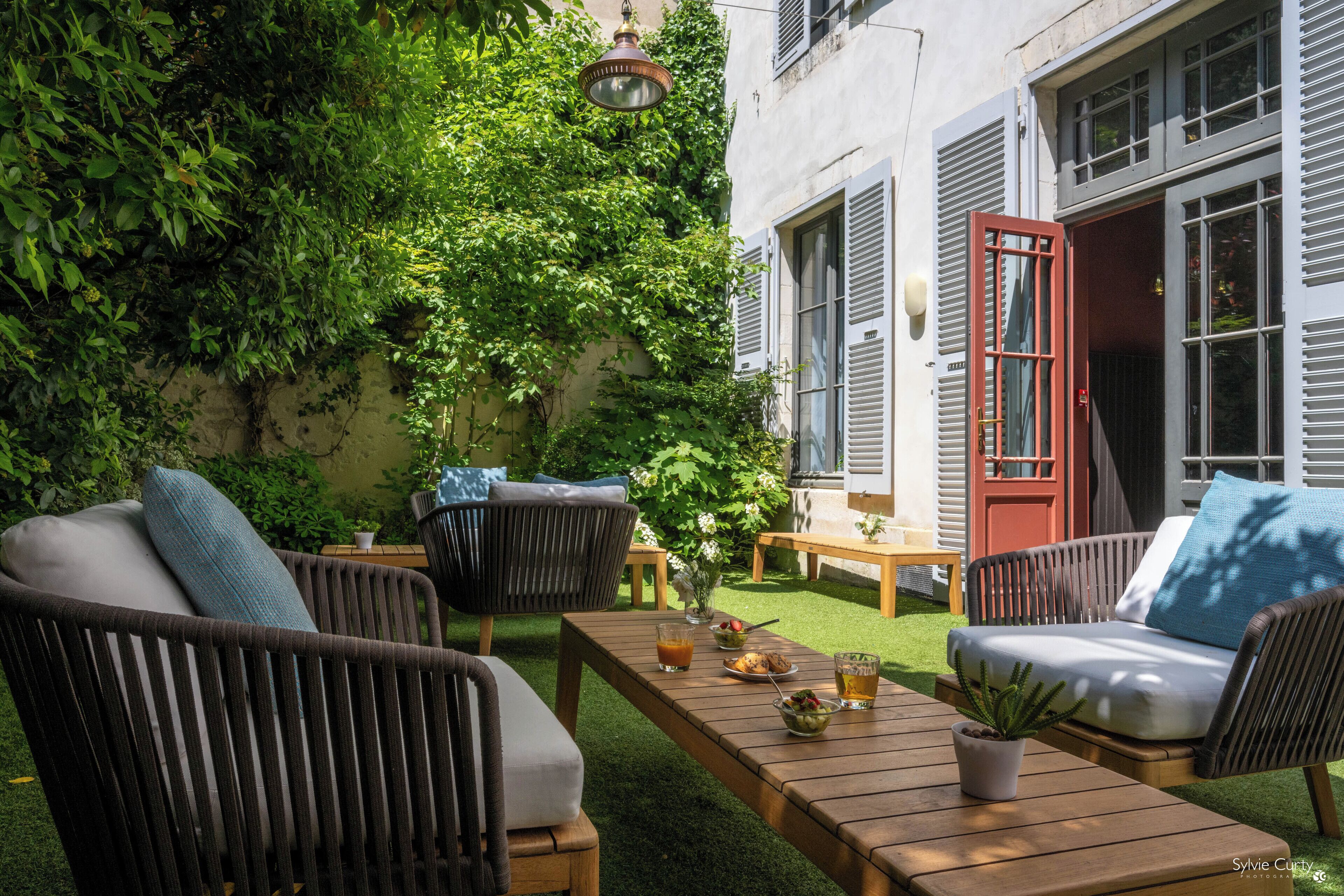 Un área de estar al aire libre con mobiliario de mimbre, una mesa de madera y una planta en maceta.
