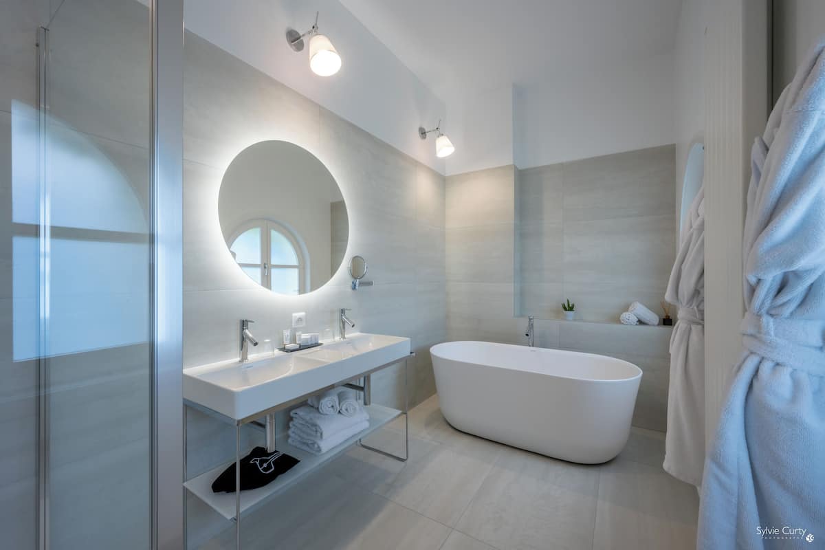 A modern bathroom with a freestanding bathtub, a large mirror, and a glass shower enclosure.