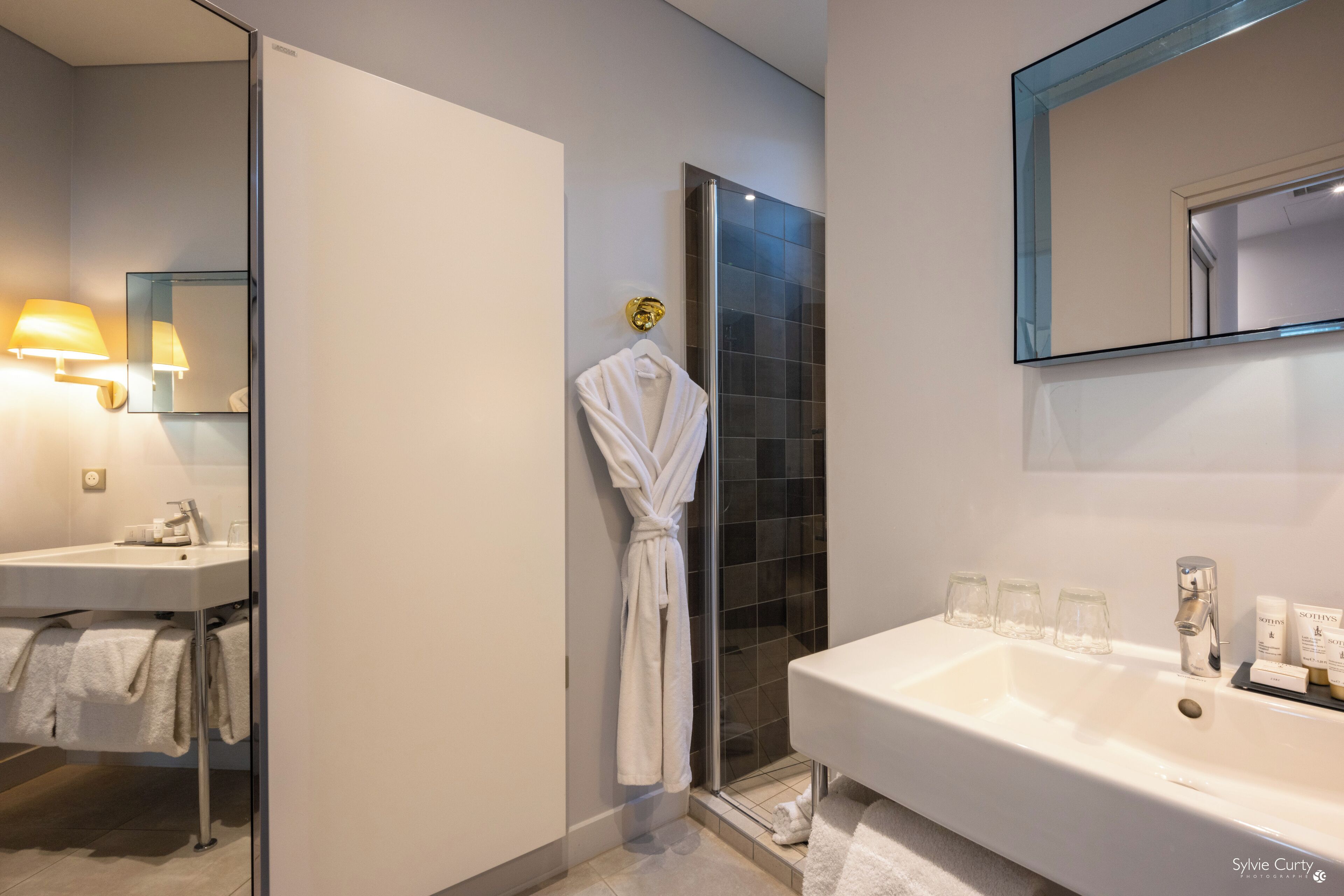 Un baño moderno con un lavamanos grande blanco, una mampara de ducha de vidrio y un espejo sobre el lavamanos.