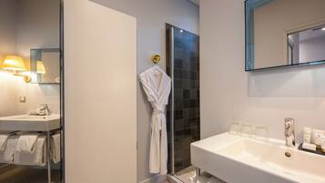 Un baño moderno con un lavamanos grande blanco, una mampara de ducha de vidrio y un espejo sobre el lavamanos.