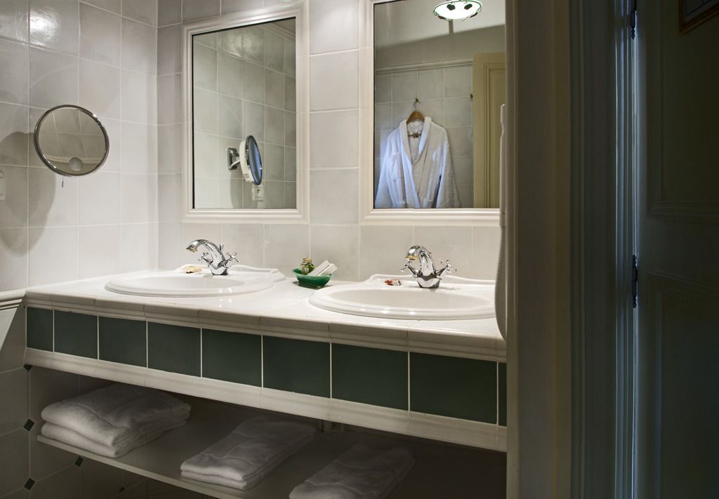 Un baño con dos lavamanos, un espejo y un perchero para toallas.