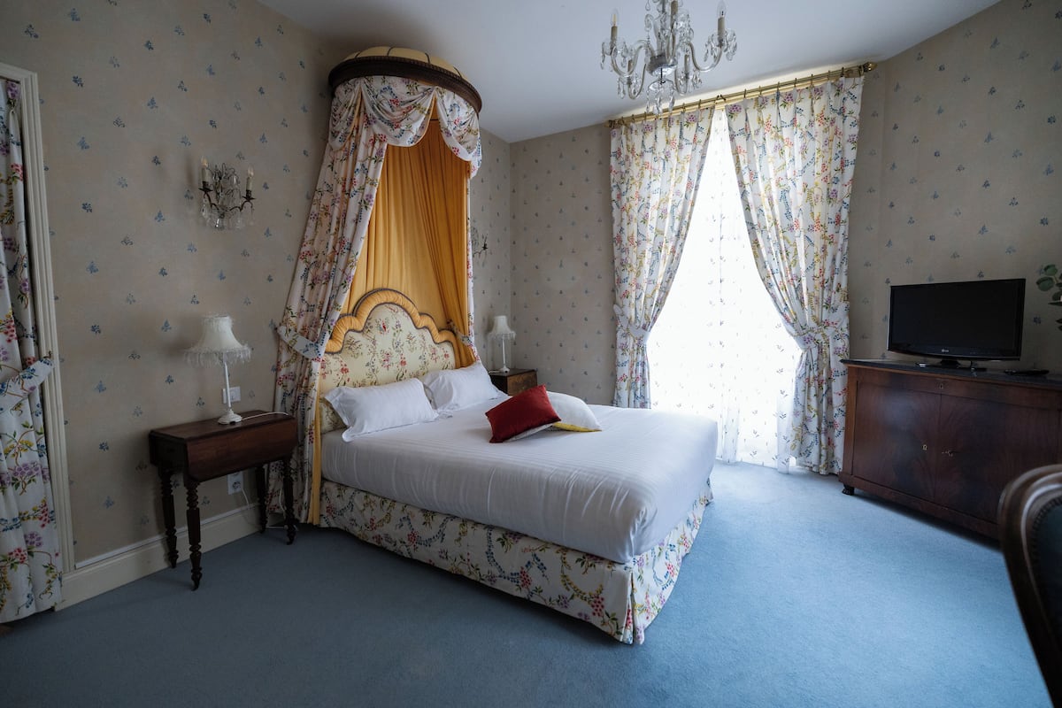 Une chambre à coucher avec un lit à baldaquin, une télévision et un lustre.