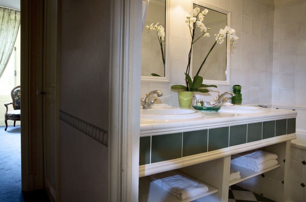 Un baño con lavamanos doble, un espejo y una orquídea en maceta.