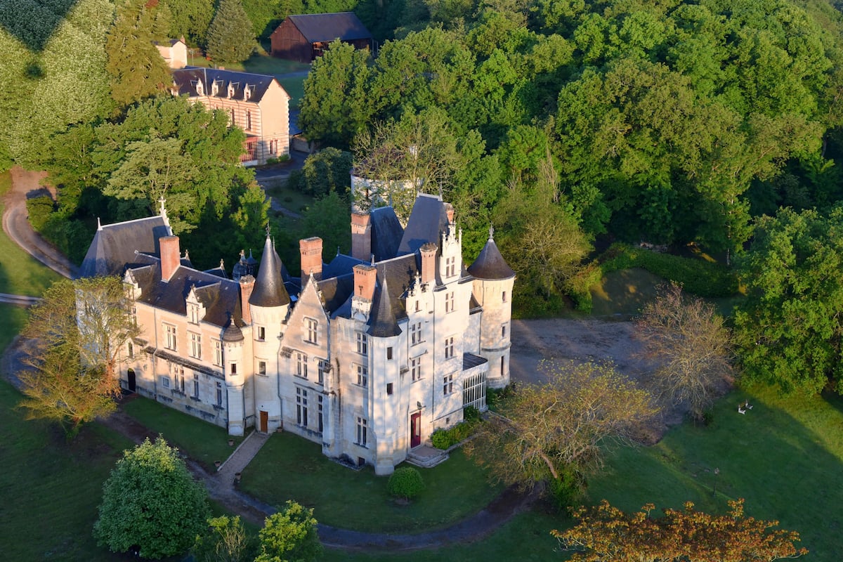 Un grand bâtiment historique doté de nombreuses tours et d’une pelouse bien entretenue.