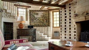 Una sala de estar acogedora con chimenea, una escalera y un tapiz grande.