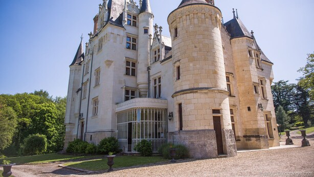 Un castillo grande e histórico con múltiples torres y un jardín bien cuidado.