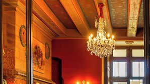 Una habitación con pared roja, un candelabro y dos sillones rojos.