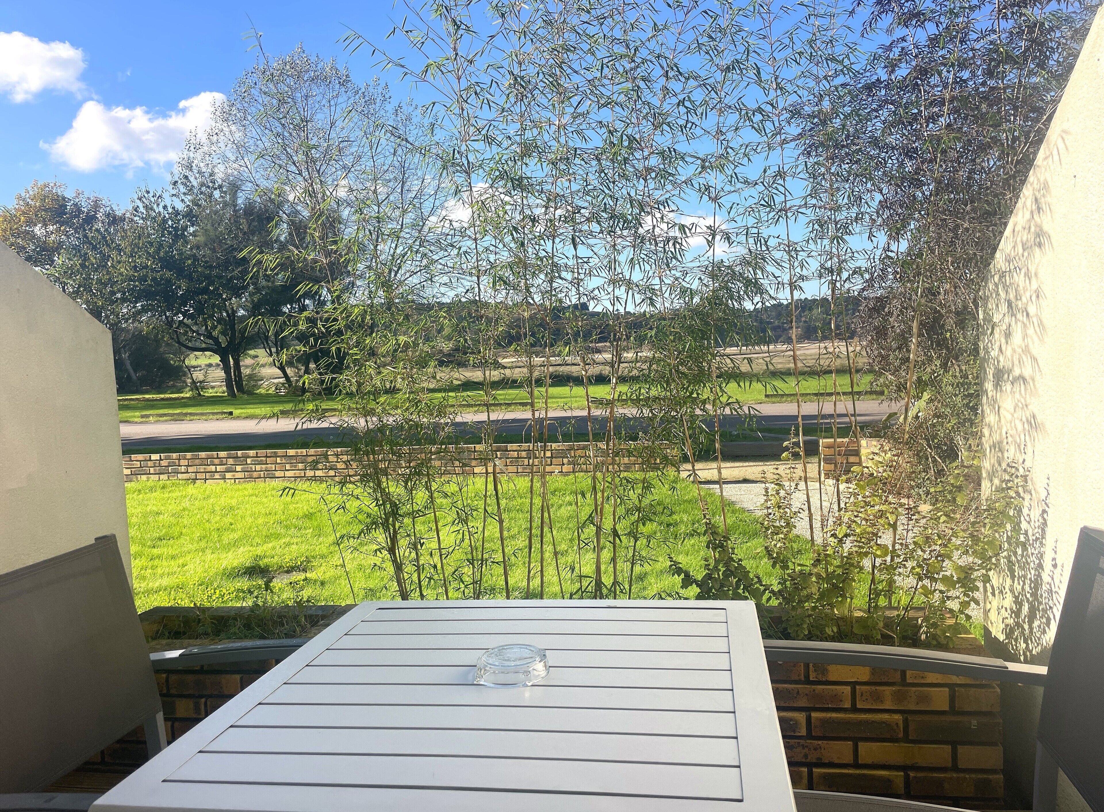 A balcony with a clear view of a grassy area, trees, and a road.