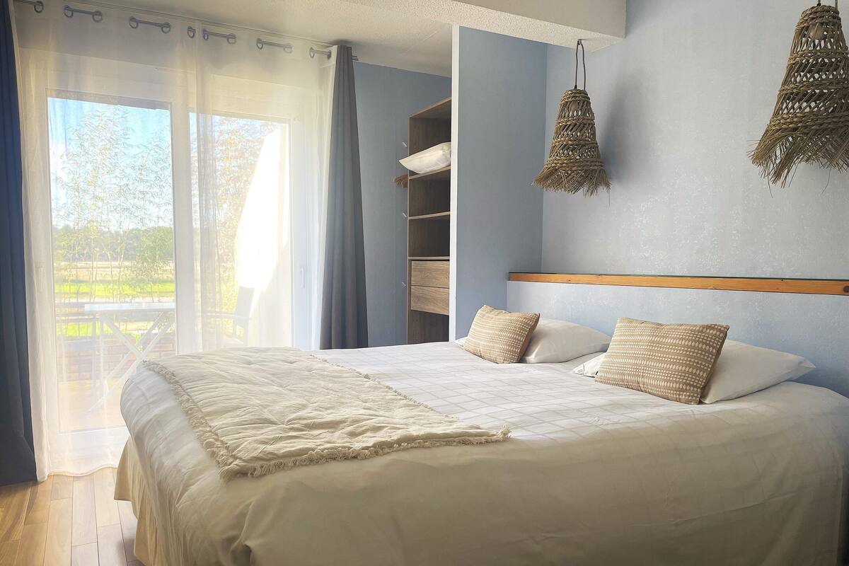 A bedroom with a large bed, a wooden headboard, a wardrobe, and a hanging light fixture.