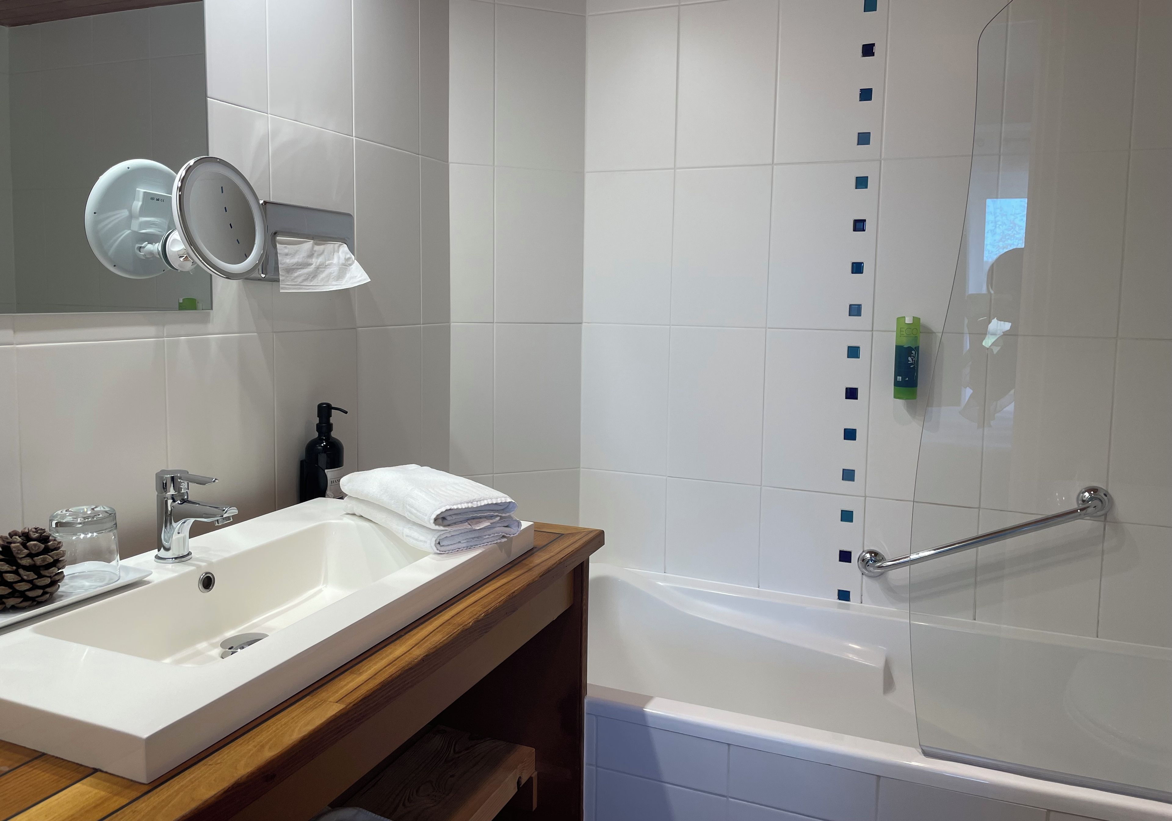 A modern bathroom with a white sink, mirror, and bathtub.