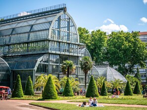 Una amplia estructura de invernadero de vidrio con techo curvo, rodeada de jardines y árboles bien cuidados.