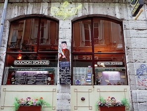 A restaurant with arched windows, a neon sign, and a menu board.