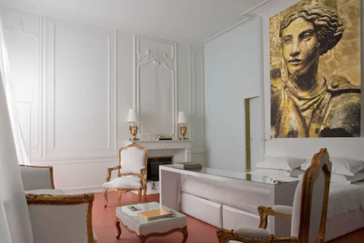 A room with a white fireplace, a large painting, and a white sofa.