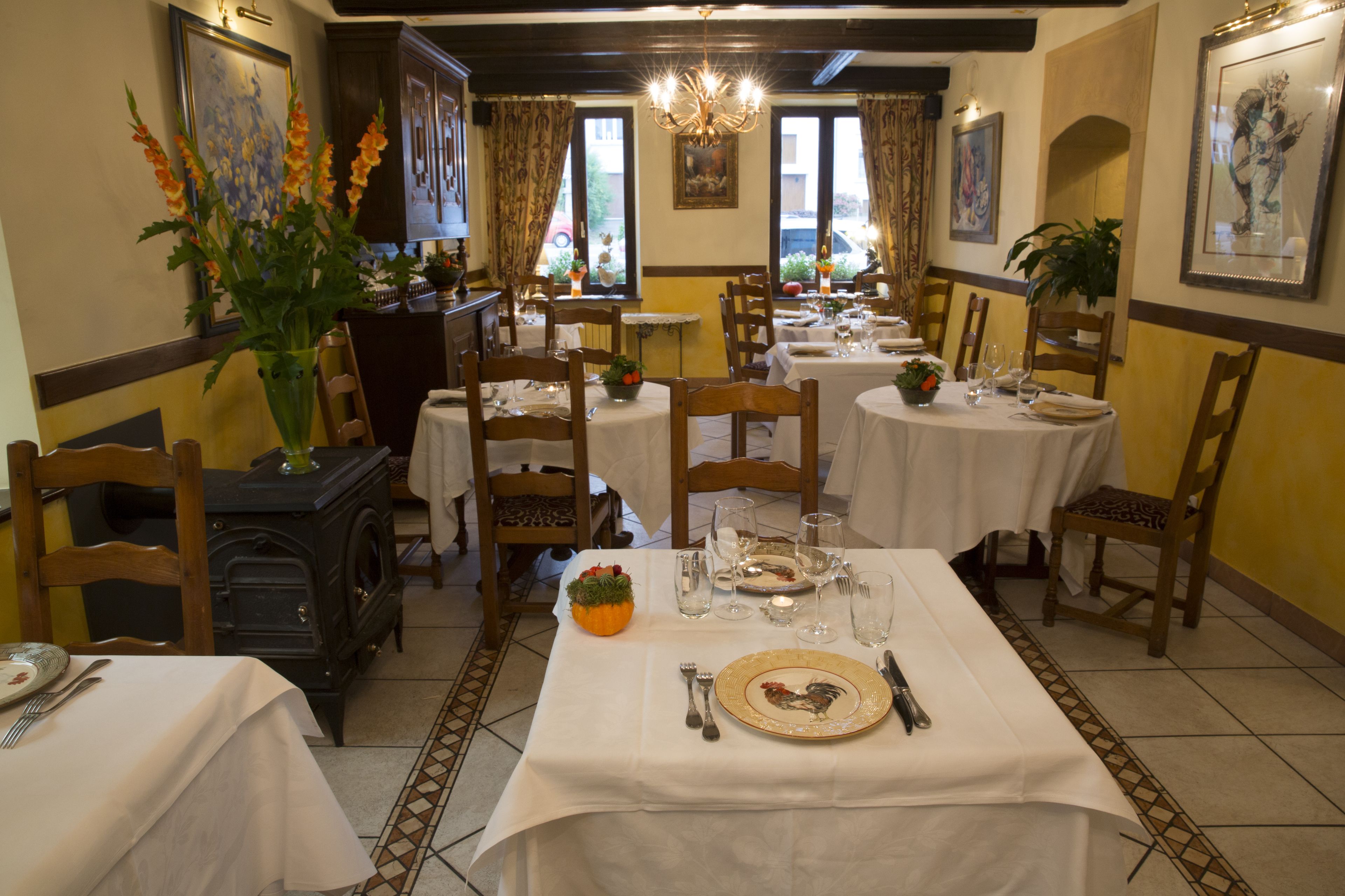 A dining area with multiple tables set for meals, wooden chairs, and a vintage stove.