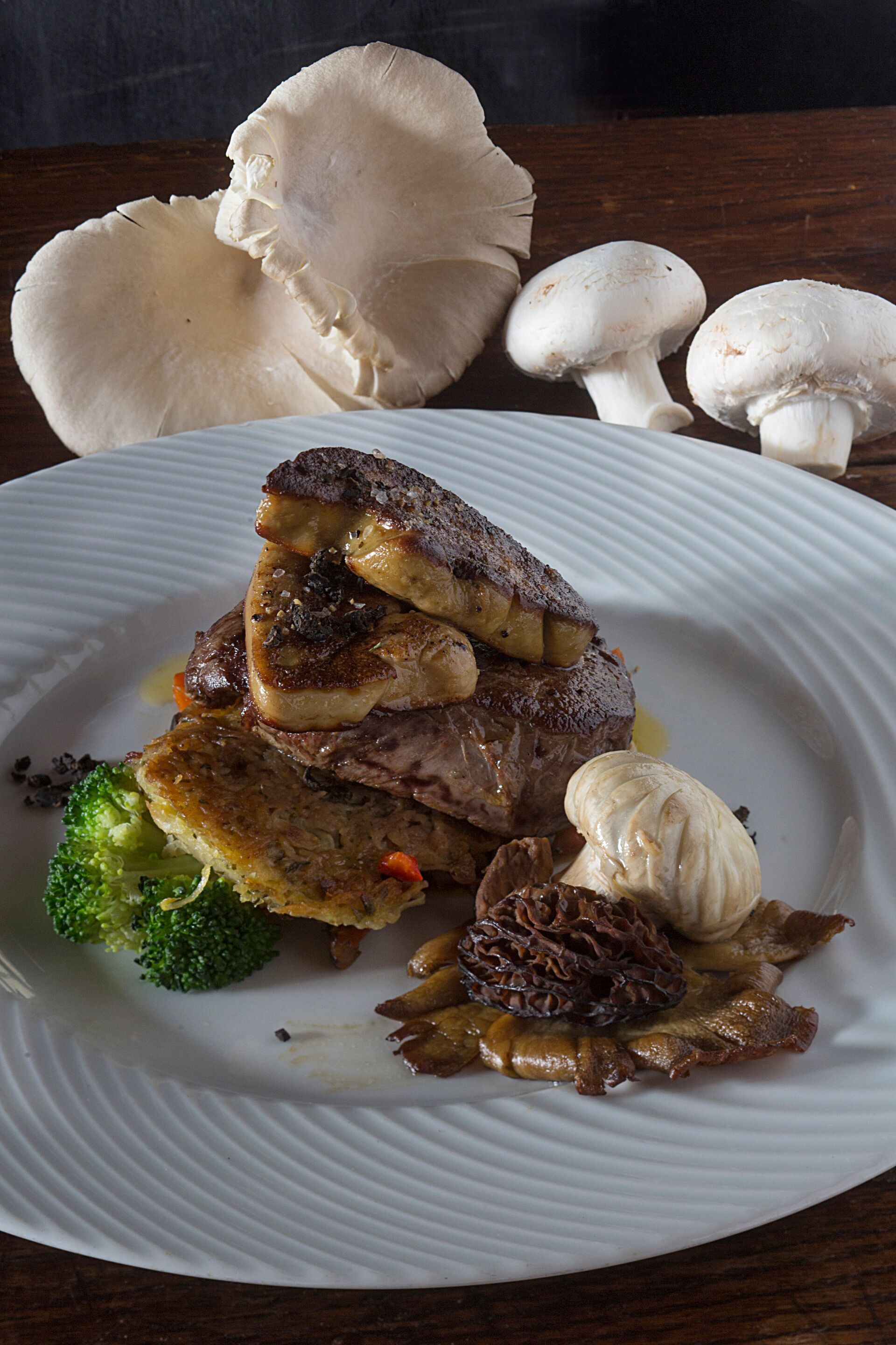 Un plato de comida con champiñones, brócoli y un trozo de carne.
