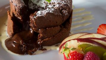 A dessert with chocolate lava cake, mint leaves, and strawberries on a plate.