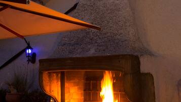 Una chimenea de piedra al aire libre con chimenea, rodeada por un muro blanco y un techo rojo.
