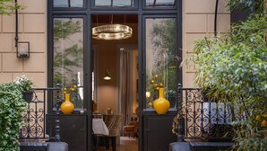 A hotel entrance with a glass door, two yellow vases on either side, a dining area with a table and chairs, and a chandelier. - Hôtel Le Paris Singulier (Paris)