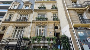A multi-story building with ornate architectural details, including balconies with wrought iron railings and flower boxes. - Hôtel Le Paris Singulier (Paris)