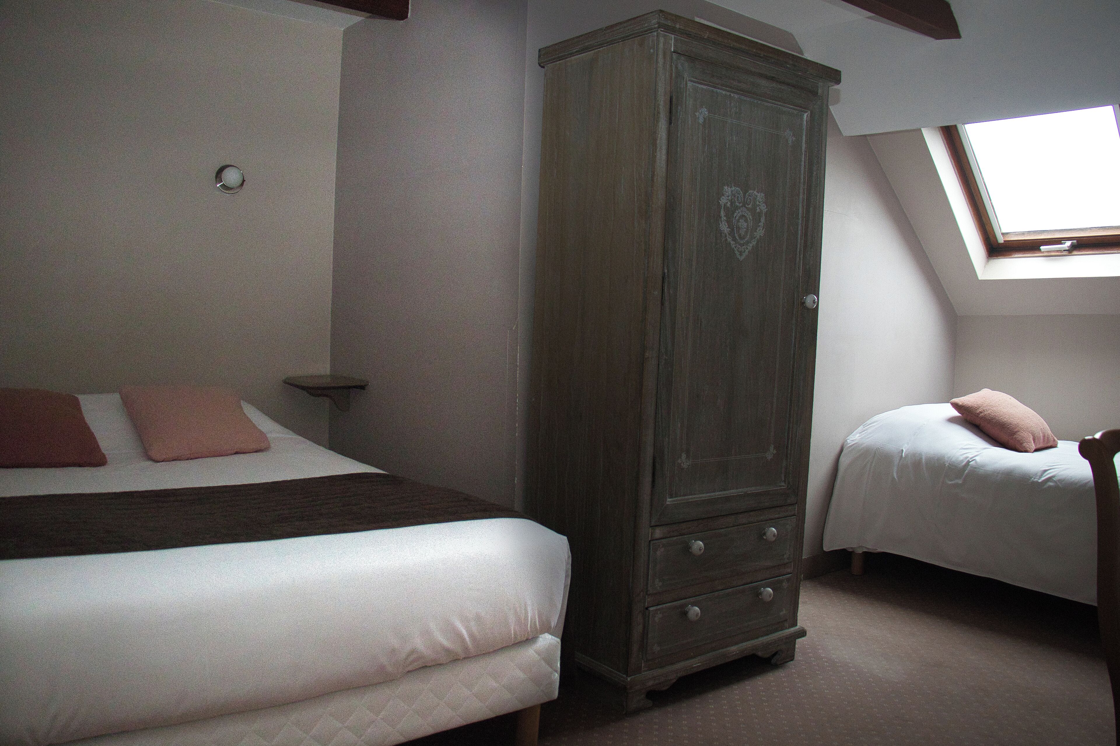 A bedroom with two beds, a wardrobe, and a skylight.