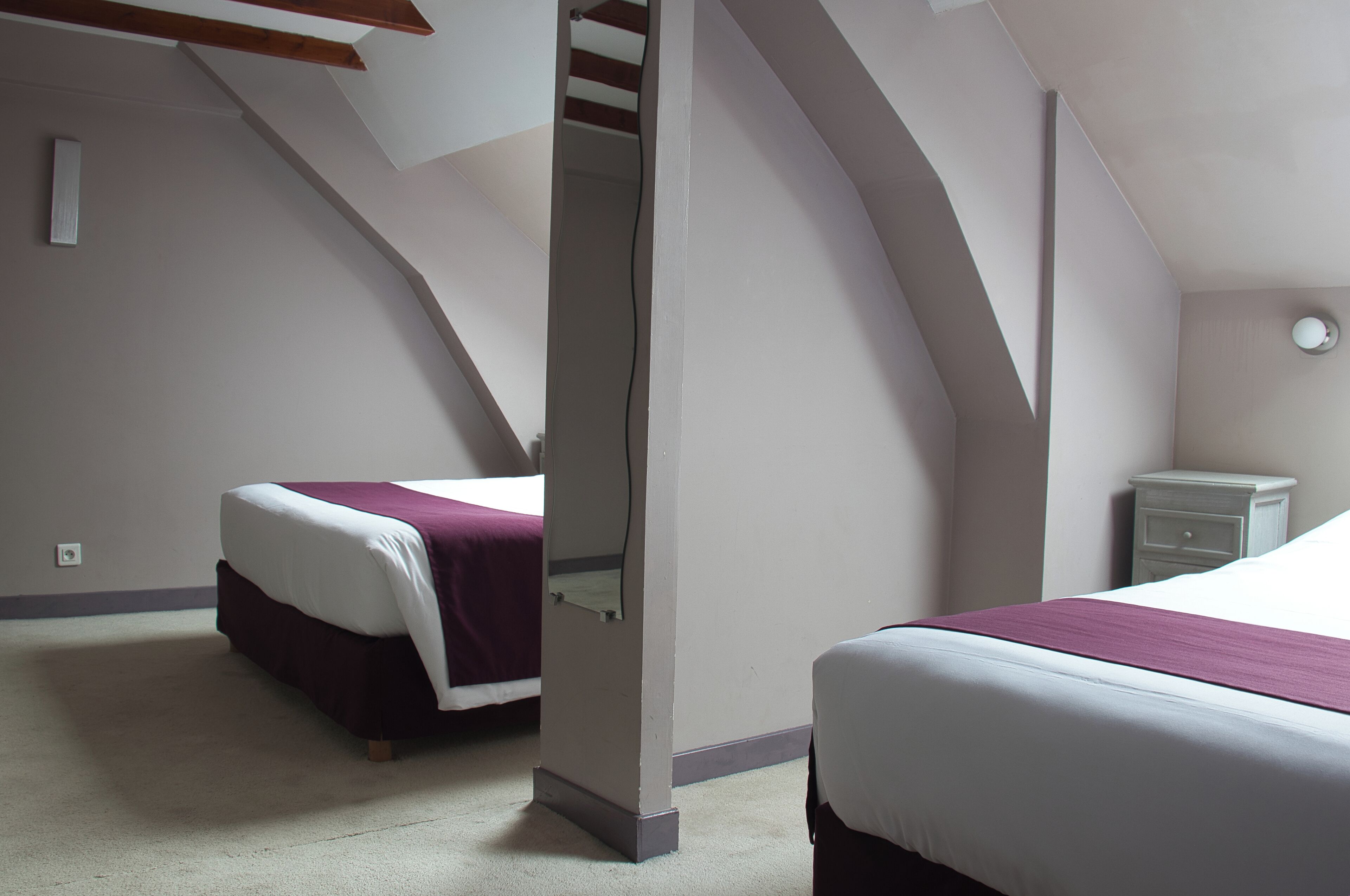 Un dormitorio con dos camas, una mesita de noche y una escalera.