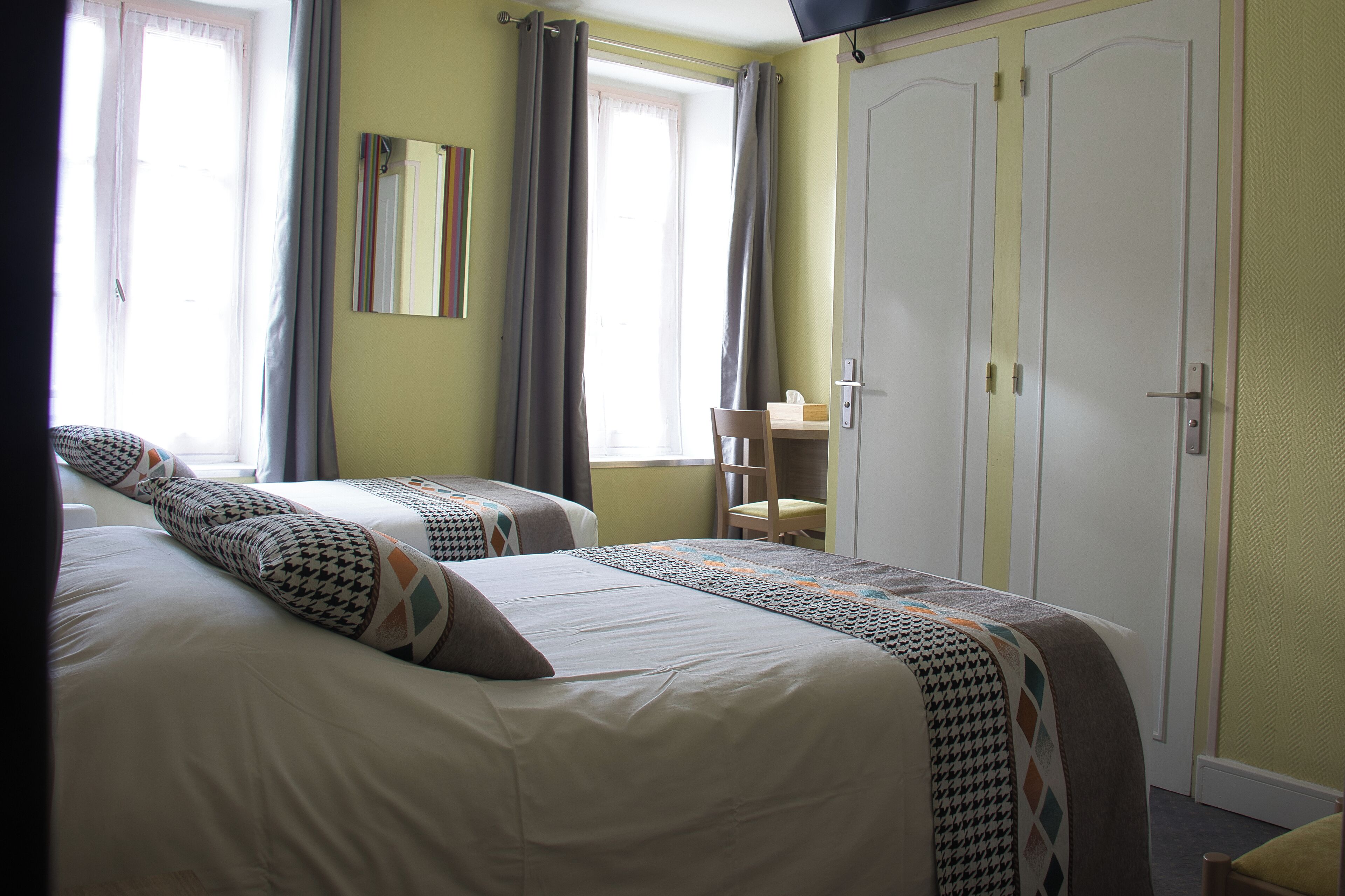 A hotel room with two beds, a desk, and a wardrobe.