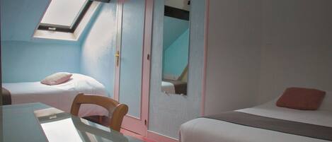 A room with a skylight, a bed with a pink pillow, a bedside table, and a chair.