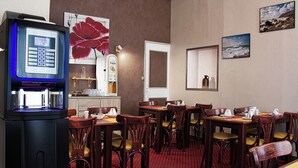 A hotel room with a minibar, a large painting of a red flower, and a view of the beach through the window. - Citotel Beausejour (Cherbourg-en-Cotentin)