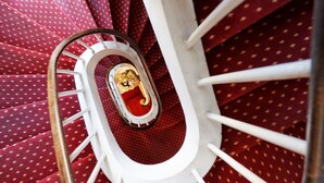A spiral staircase with a red patterned carpet and white balusters. - Citotel Beausejour (Cherbourg-en-Cotentin)