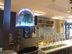 Ein Heineken-Getränkespender mit transparenter Kuppel, einem digitalen Display und einem Zapfhahn.